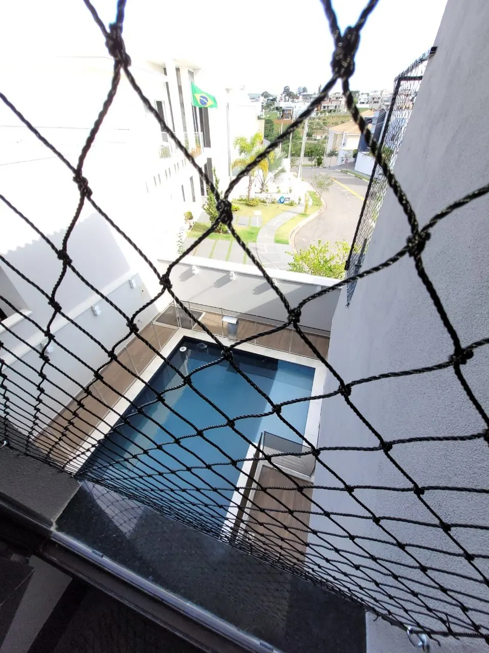 Rede de proteção preta em varanda com vista para piscina no andar de baixo