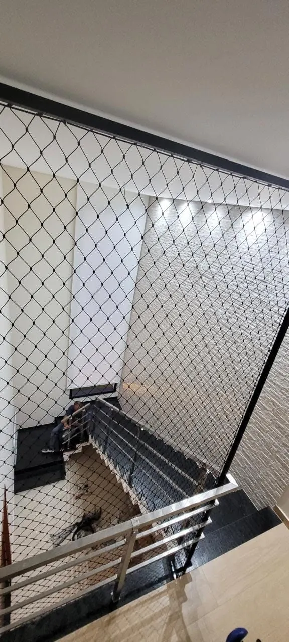 Vão de escada interna protegido com rede de proteção preta instalada pela Barbosa