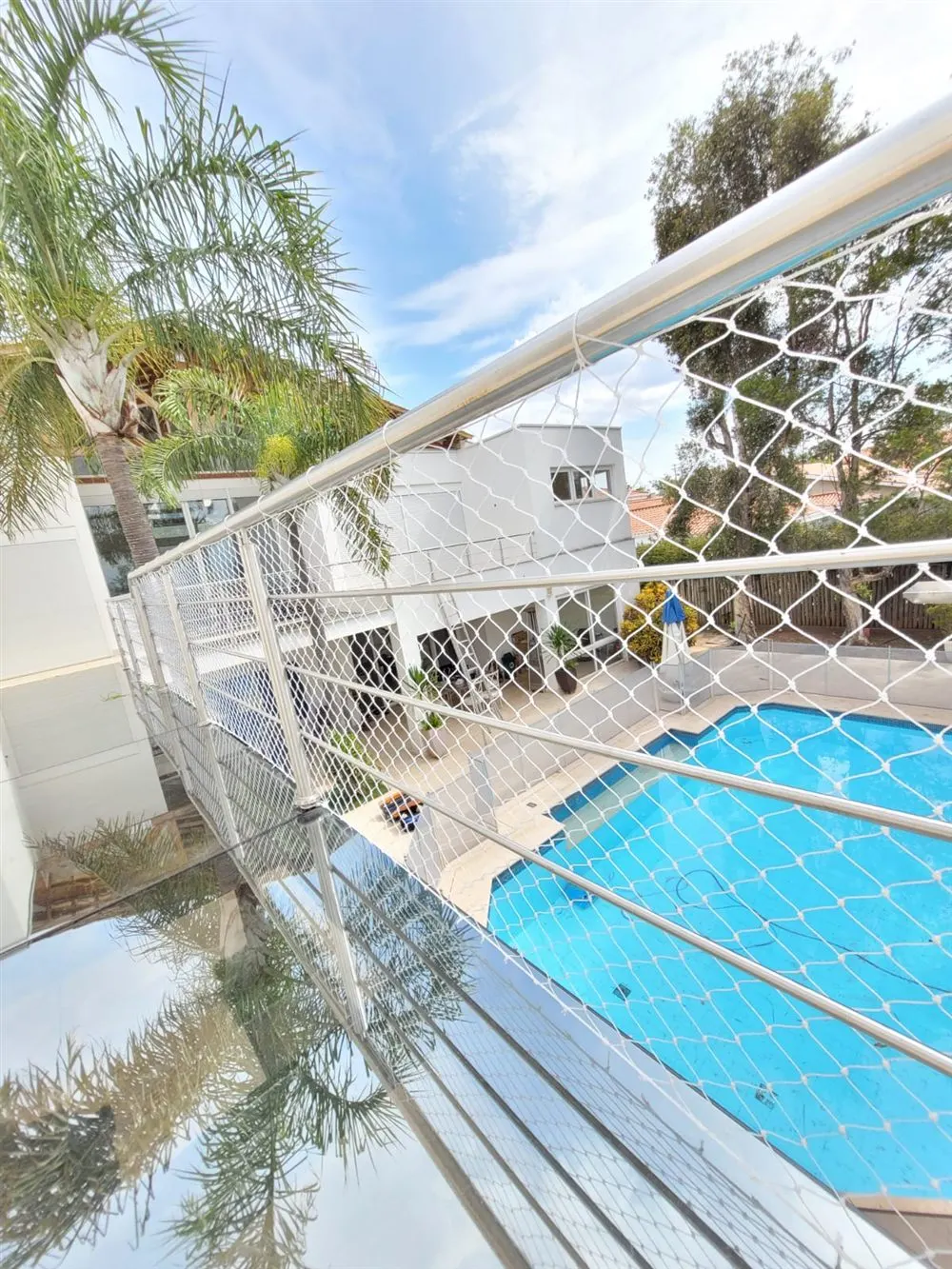 Rede de proteção branca sobre área de piscina residencial instalada pela Barbosa