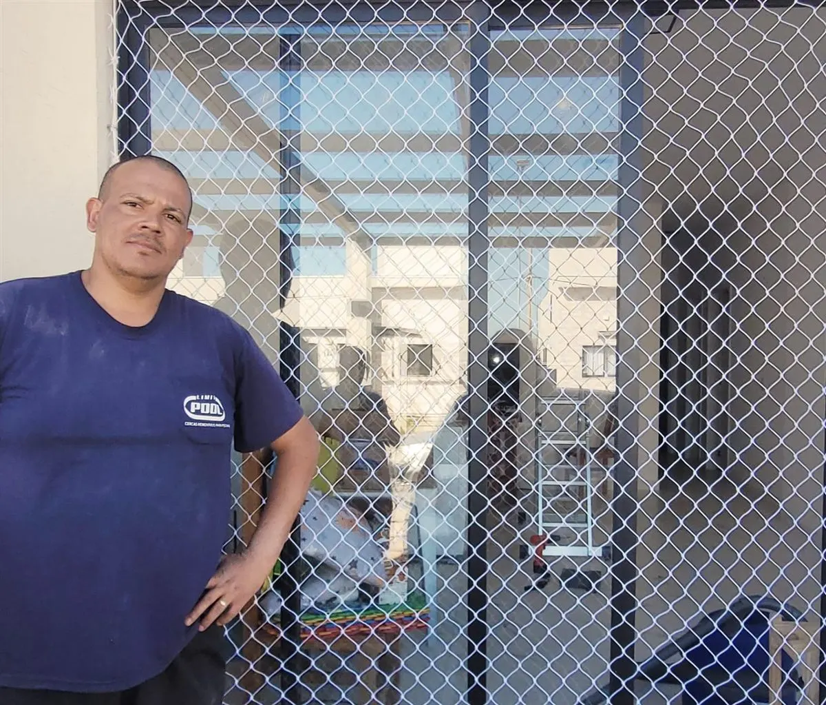 Instalador da Barbosa Redes de Proteção em frente a uma rede instalada em área externa de residência